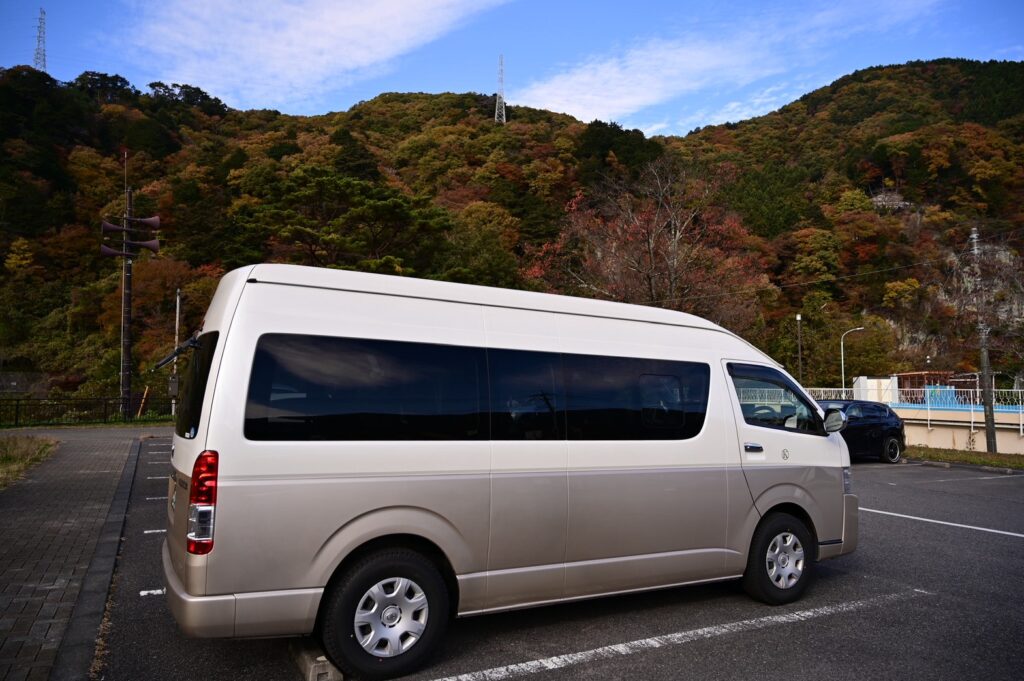 駐車場に停車しているハイエースのジャンボタクシー。観光送迎用の大型車両の外観。