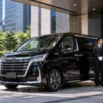 オフィス街で役員車に寄り添うハイヤー経験のあるドライバー