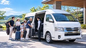 大人数と大きな荷物を乗せて停まる白い貸切ジャンボタクシー（トヨタ・ハイエース ワイド）