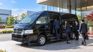 企業視察の送迎で工場前に待機する黒い貸切ジャンボタクシー（トヨタ・ハイエース ワイド スーパーロング）